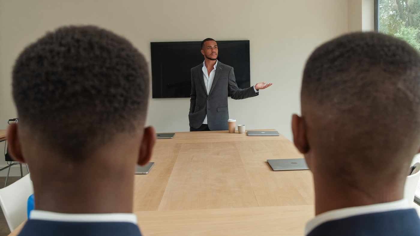 A facilitator standing at a table teaching a small team of professionals in a daylit office